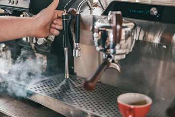 Coffee machine in steam, barista preparing coffee at cafe