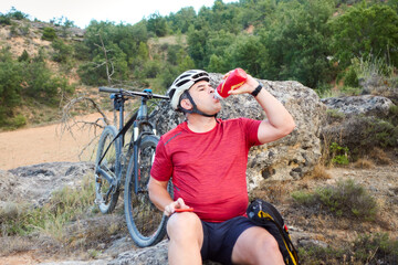 Naklejka premium a male cyclist drinking water, hydration during sport