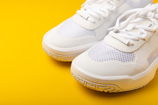 White sneakers on a yellow background.Fashion.UNISEX. Sneakers are sports shoes for an active lifestyle. Product photo and levitation concept. Street style. Copy space. Place for text.