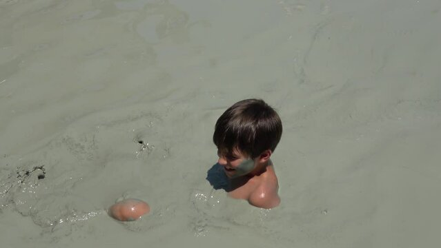 Koycegiz, Mugla, Turkey - 3d of August 2022: 4K Child enjoys mud bath
