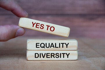 Hand holding yes to equity and diversity text on wooden blocks.