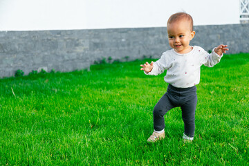 Baby learning to take first steps outside on lawn