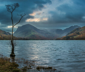 Epic Autumn sunrise landscape image of Buttermere in Lake District with dramatic stormy sky