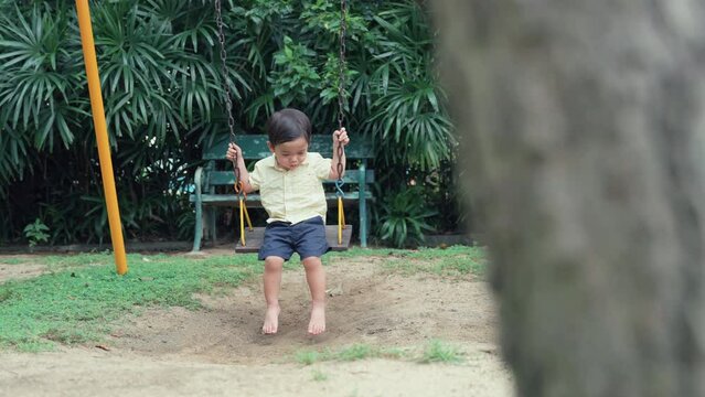 Cute little boy Asians are playing on the swings in the playground alone.