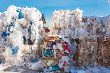 stacks of old waste paper and plastic waste in front of recycling facility