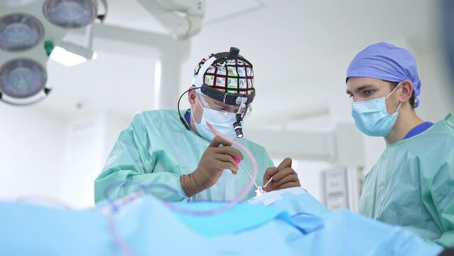 Surgeon otolaryngologist performs nasal operation. Professional in device glasses uses instruments to conduct surgery. Blurred backdrop.