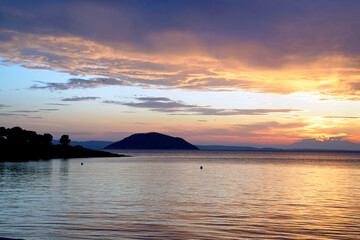 Obraz premium Coast of the Aegean Sea in Sithonia. Greece. Warm sunny September evening. Colorful sky before sunset. Bright reflections on the surface of the water.