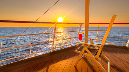 Vue d'une chaise longue avec un cocktail sur le pont d'un navire de croisière au coucher de soleil...