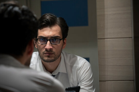 Tired Handsome Businessman Standing In Front Of Mirror In The Toilet After Exhausting Busy Workday