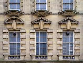 Fototapeta na wymiar Three Art Deco window, detail of a stone builing with typical Art deco ornaments