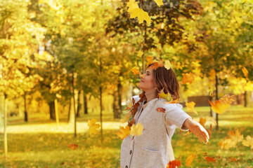 Attractive woman with yellow leaves having fun outside in autumn park