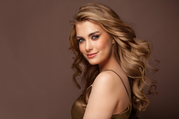 Beautiful glamorous model woman with long wavy and shiny hair against brown studio wall banner background