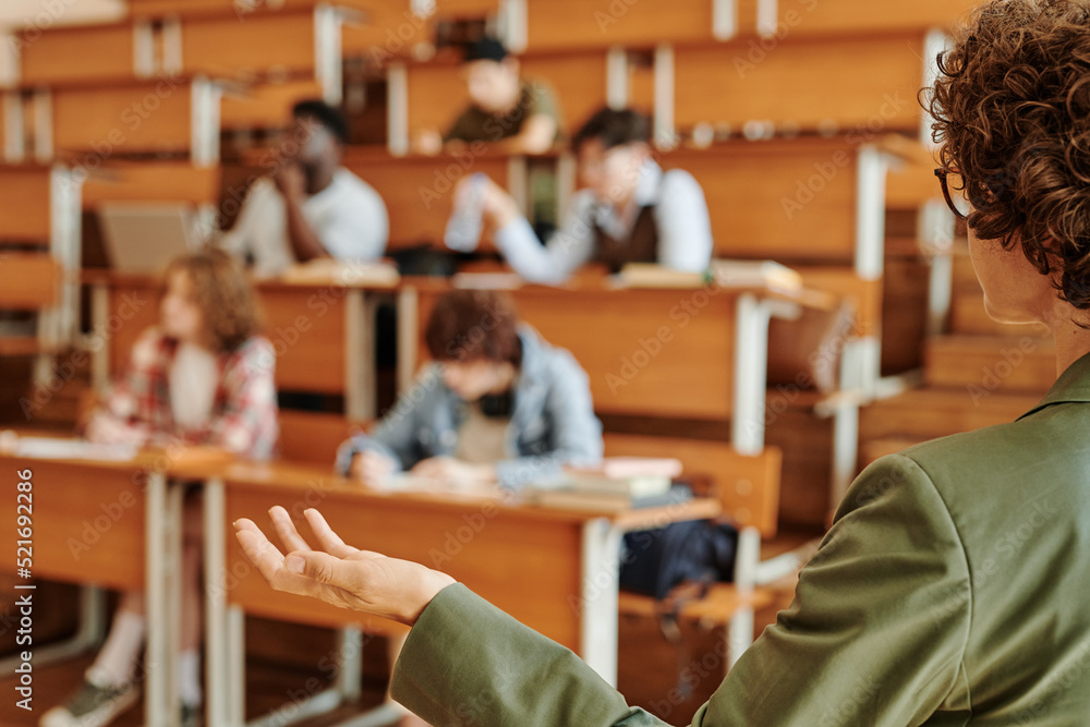 Poster young confident college teacher or lecturer explaining one of lesson points while standing in front 