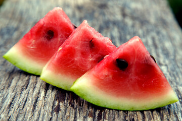 Juicy fresh red watermelon on the table. Watermelon sliced into pieces on a wooden texture background. The concept of food, happiness, sweets and desserts.
