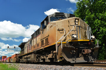 Fototapeta na wymiar Diesel locomotive pulling a freight train of container cars