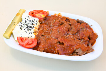 Turkish and Arabic Traditional Ramadan doner kebab with tasty tomato sauce and rice or turkish pilav in white plate on wood table background. ( , Iskender, ekmek arasi pilav ustu doner, doner durum )