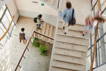Blurry motion of multicultural teenage male and female students of highschool on staircases inside...