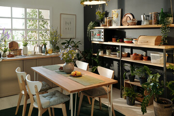 Part of spacious cozy kitchen with sustainable table, kitchenware and house plants creating...