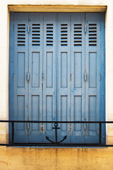 Große blaue Holzfalttür mit schwarzer Brüstung mit Ankermotiv davor, vertikal