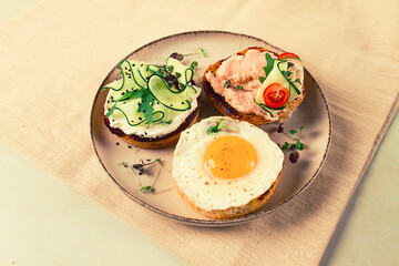 Assortment of sandwiches, white bread, fried egg, cream cheese and cucumber, capelin caviar, sesame bun, breakfast, on a white table, no people,