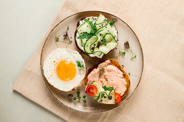 Assortment of sandwiches, white bread, fried egg, cream cheese and cucumber, capelin caviar, sesame bun, breakfast, on a white table, no people,