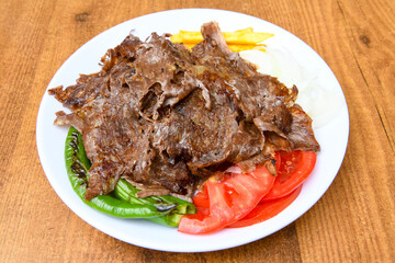 Turkish and Arabic Traditional Ramadan doner kebab with tasty tomato sauce and rice or turkish pilav in white plate on wood table background. ( , Iskender, ekmek arasi pilav ustu doner, doner durum )