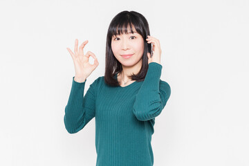 白背景の前で、スマホで会話をしている女性