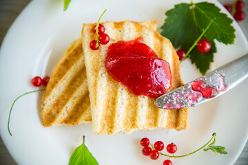 fried bread croutons for breakfast with redcurrant jam in a plate with berries
