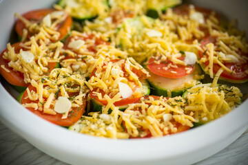 raw zucchini and tomatoes sliced with cheese, prepared for baking