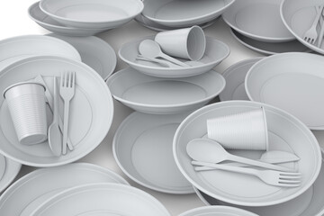 Heap of disposable utensils like plate, folk, spoon,knife and cup on white.
