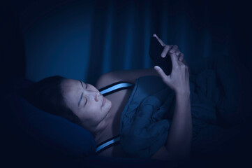 Fototapeta na wymiar Asian woman play smartphone in the bed at night,Thailand people