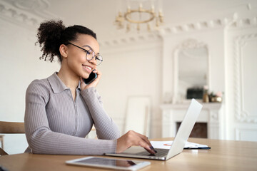 Obraz premium A woman in an office with glasses works, uses a laptop, answers the client's mail and phone