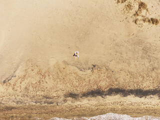 Aerial top view of a man lying on a beach and sunbathing alone