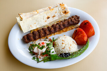 Grilled Turkish Adana, Urfa  Kebab with grilled vegetables, onion and rice on plate. Adana durum.
