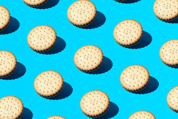 Trendy pattern made of old fashioned sandwich cookies on bright blue background. Minimal coffee snack concept. 