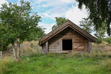 Fototapeta na wymiar Small pasture storage cottage in green field.