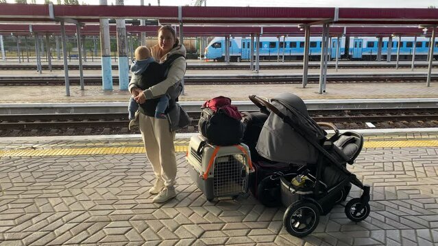 Family with little child traveling by train, woman with baby and luggage on Simferopol railway station platform waiting for arrival of the train.