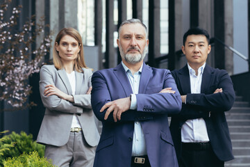 Fototapeta na wymiar Portrait of serious diverse business team, employees with boss together looking at camera seriously and thoughtfully, group of business people outside office in business suits