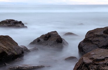 Fototapeta na wymiar Waves crashing on rocks in a long exposure shot