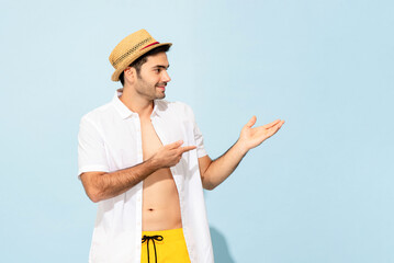 Handsome Caucasian man in summer outfit smiling and pointing hands up aside in studio light blue color isolated background