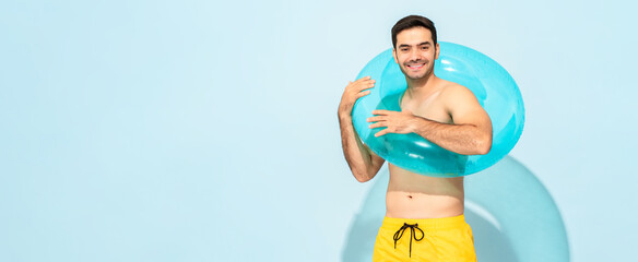 Portrait of young handsome shirtless caucasian smiling man wearing inflatable ring and enjoying pool party at weekend isolated on blue background