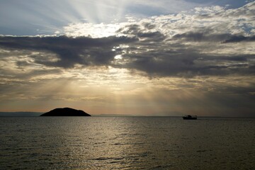 Horizontal shot. Empty beach in the evening at sunset. . Silhouettes and coastline. Sea bright sky. Greece Sithonia. Horizon. Clouds and rays of the sun. Bird island