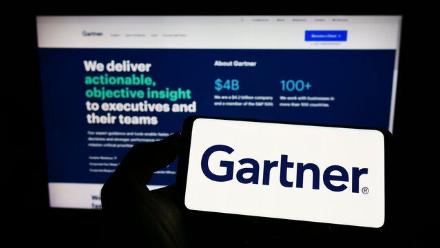 Stuttgart, Germany - 07-30-2022: Person holding mobile phone with logo of American research company Gartner Inc. on screen in front of business web page. Focus on phone display.