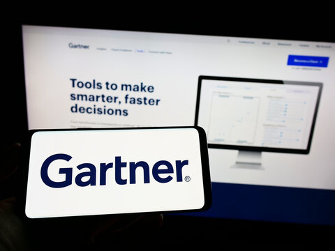 Stuttgart, Germany - 07-30-2022: Person holding cellphone with logo of US research company Gartner Inc. on screen in front of business webpage. Focus on phone display.