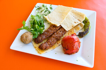 Grilled Turkish Adana, Urfa  Kebab with grilled vegetables, onion and rice on plate. Adana durum.