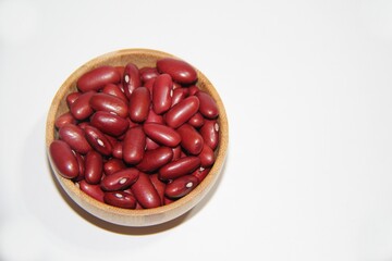 Red beans in a wooden bowl on a white background. Top view with copy space.