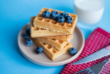 sweet dish Belgian waffles with blueberries on a blue background