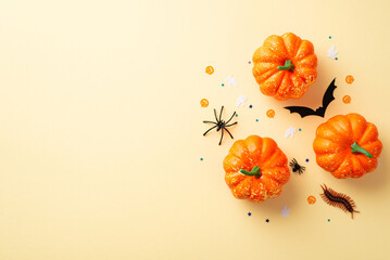 Halloween concept. Top view photo of pumpkins bat silhouette spiders centipede and confetti on isolated beige background with empty space