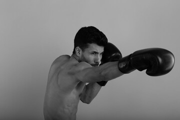 Fototapeta na wymiar Training of a young strong boxer in black and white