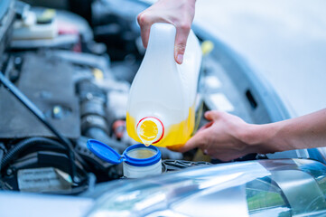 Pouring antifreeze. Filling a windshield washer tank with an antifreeze in summer hot weather.